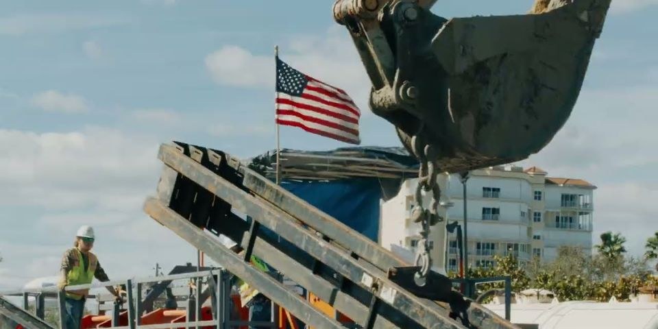 Excavator bucket and American flag on a TB Landmark job
