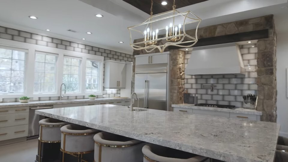 Kitchen with a marble island, pendant chandelier and stone accents in a luxury listing