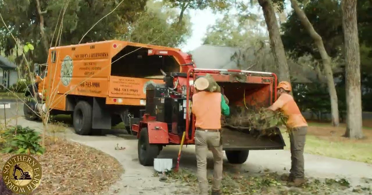 Southern Earthworks crew feeding brush into a chipper beside their truck